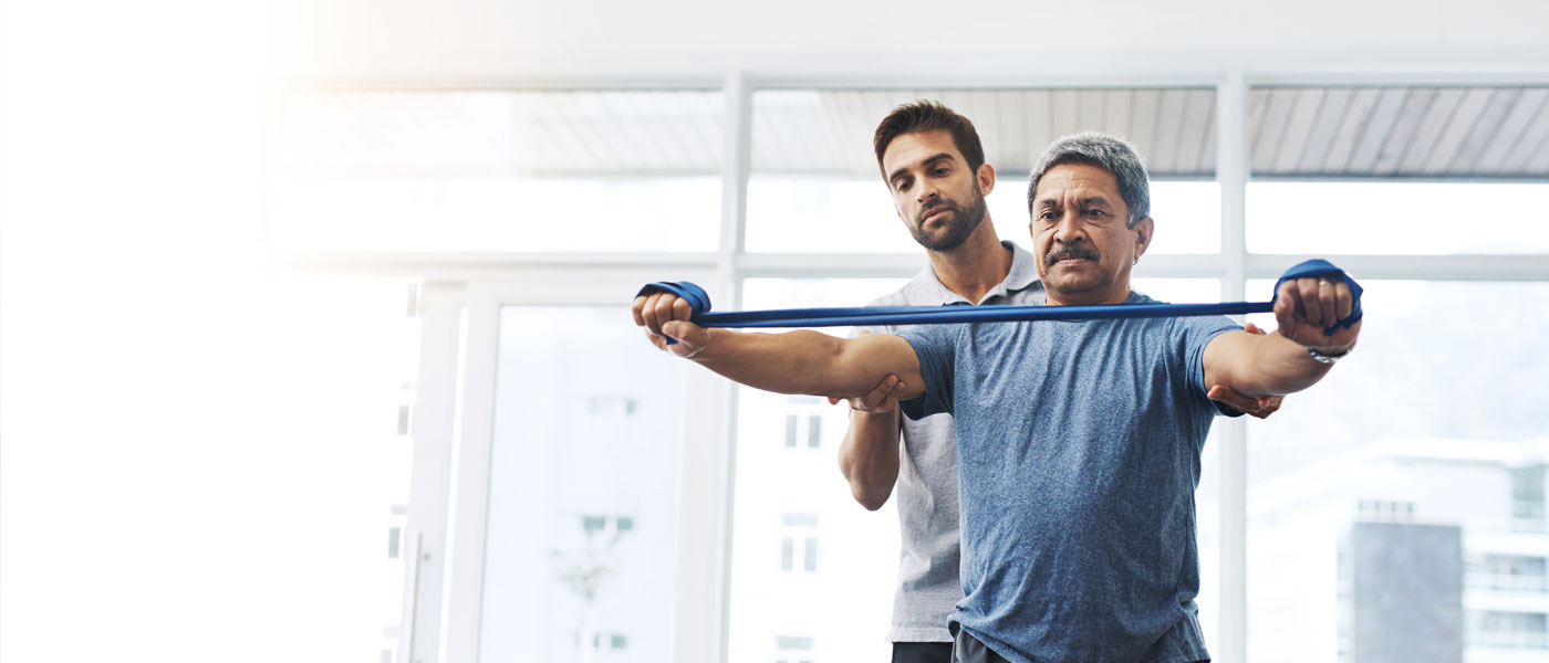 Physical therapist spotting a patient who is using resistance bands